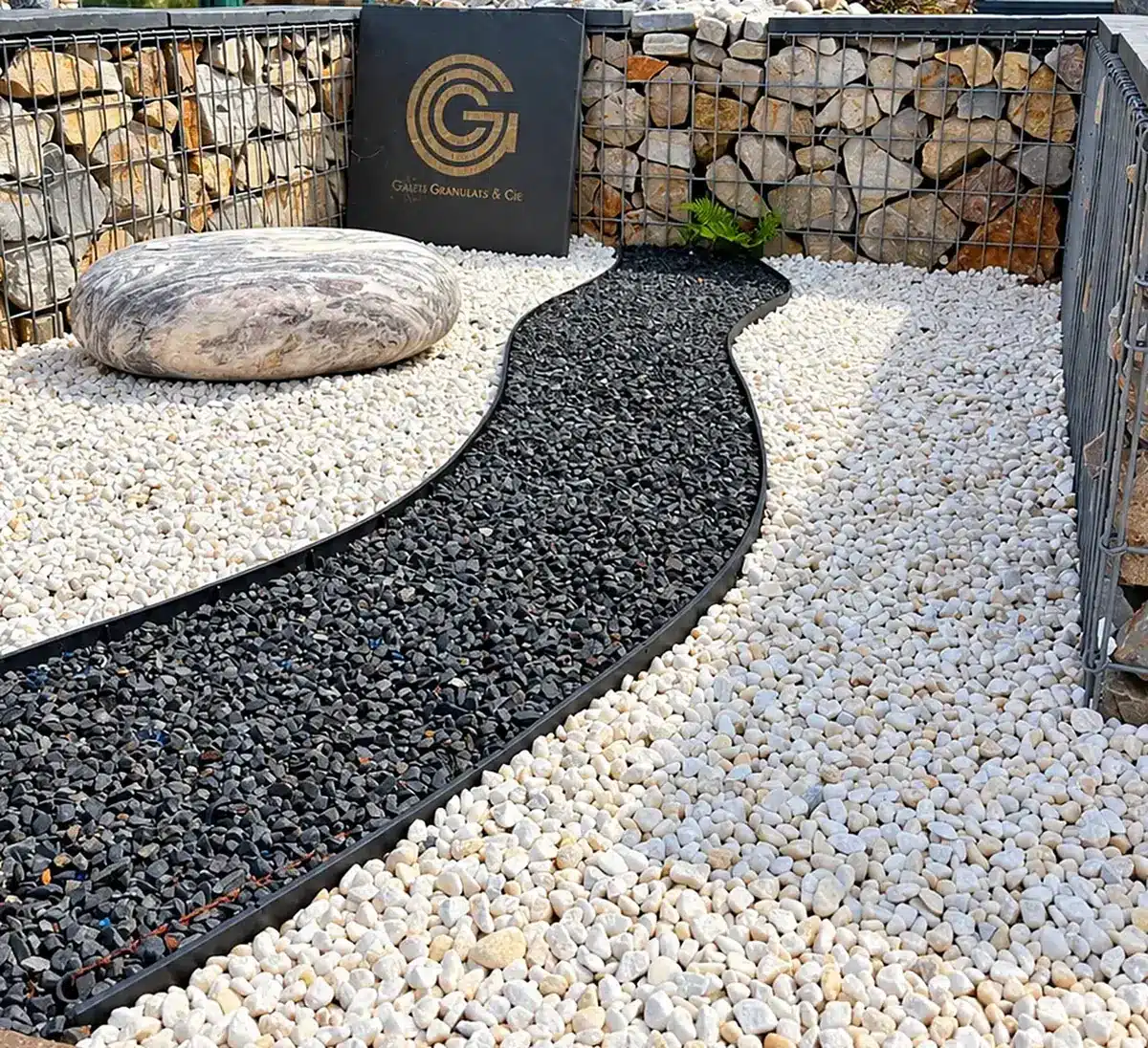 Allée de gravier noir et gravier blanc bordée de gabions